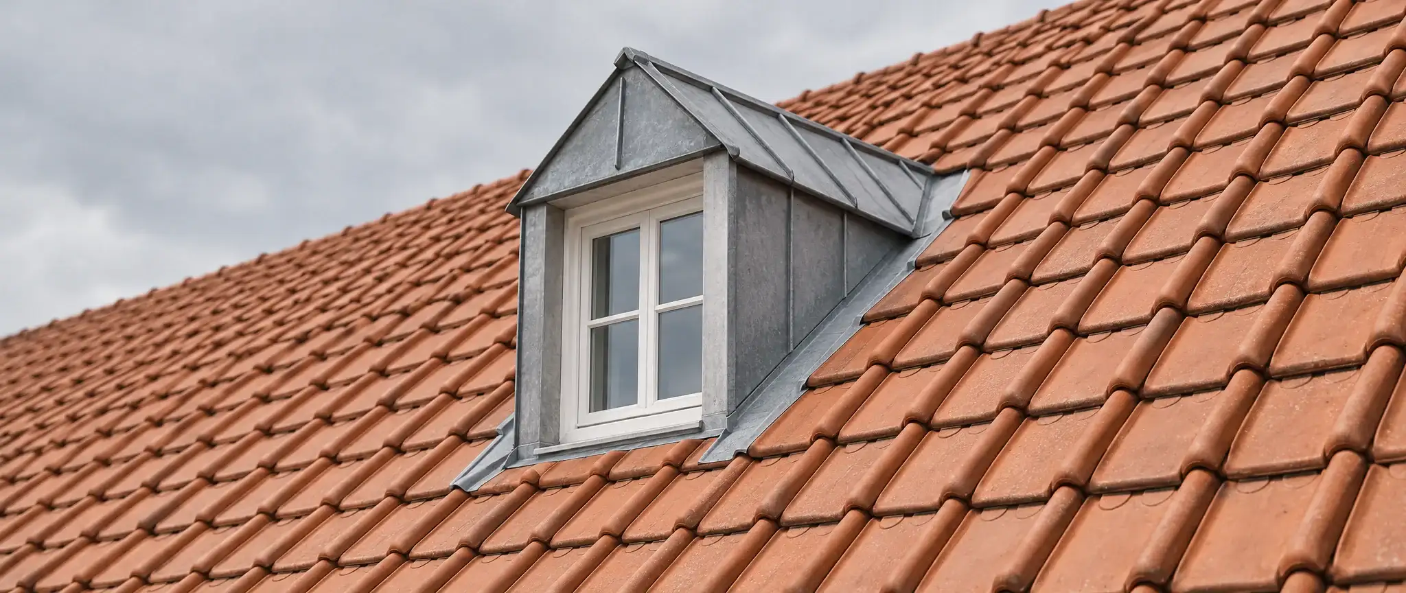 Zones d’intervention d’un couvreur autour de Dunkerque : lucarne à joues de zinc sur une toiture de tuiles